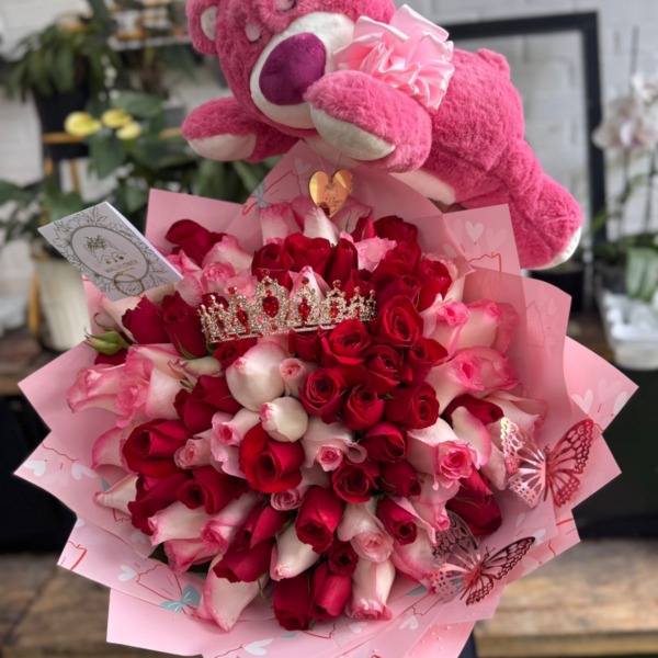 Ramo de rosas rojas y rosadas con corona de pedrería junto a un peluche rosado grande — Wallflower Guatemala