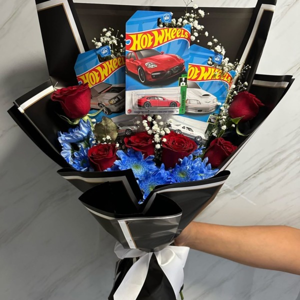 Ramo de rosas rojas y margaritas azules con tres carritos Hot Wheels y papel negro — Wallflower Guatemala