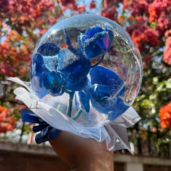 Orquídeas azules dentro de una burbuja transparente con tul blanco y listón azul — Wallflower Guatemala