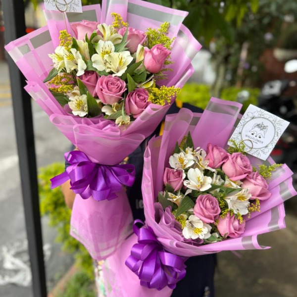 Dos ramos de rosas rosadas y astromelias blancas en papel rosado con listón morado — Wallflower Guatemala